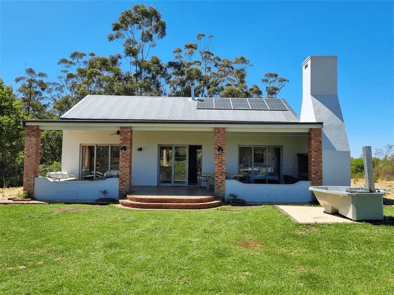 Tolbos Cottage at Bokrivier: White cottage on green lawn under blue sky
