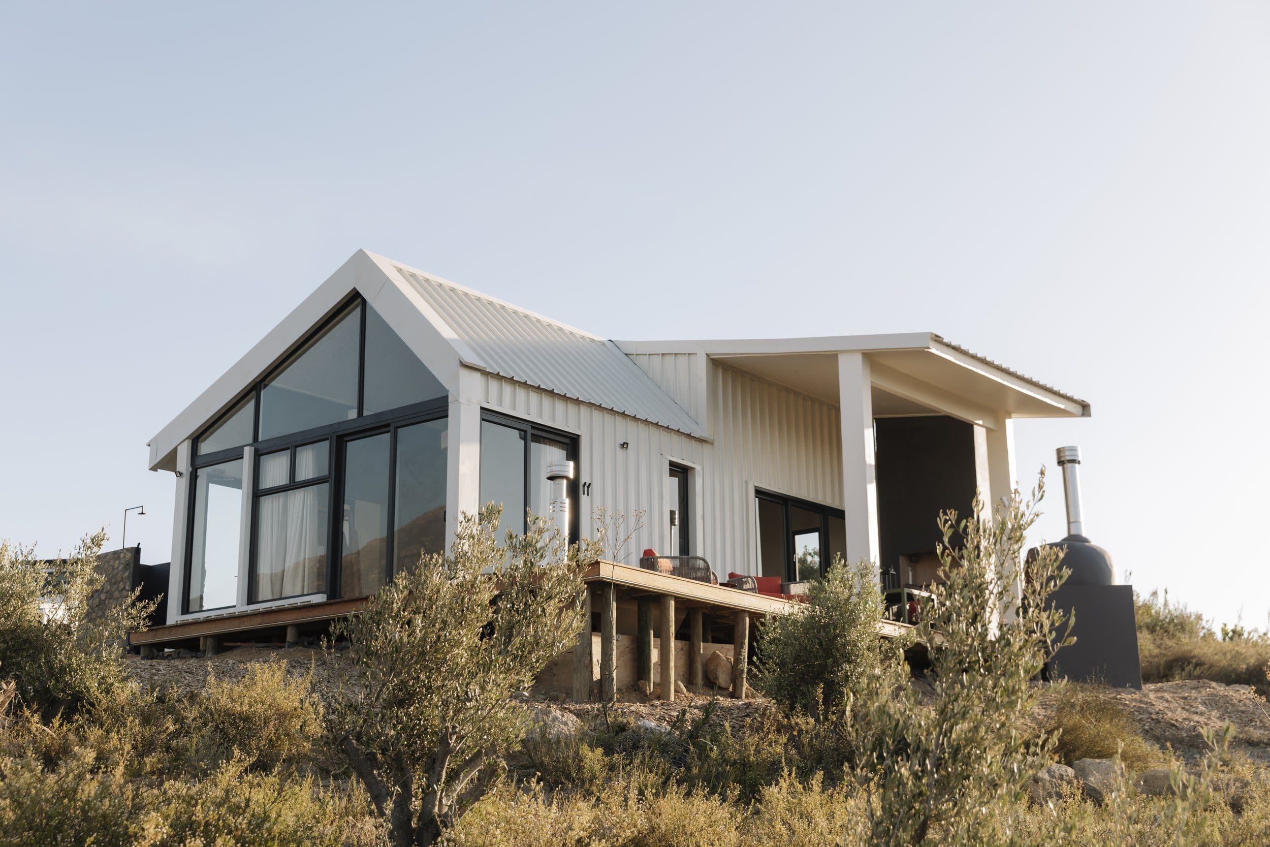 Hemingway Untether Luxury Pod: Modern pod cabin on a hillside among olive trees at dusk