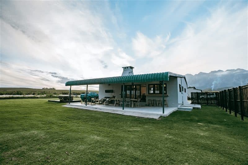 Western Cottage at Bokrivier: White cottage with covered patio, dramatic dusk sky and mountains