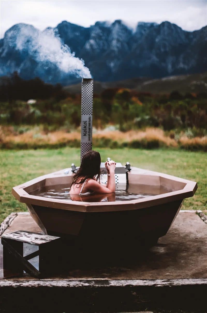 Barton Cottage at Bokrivier: Woman in steaming wood-fired hot tub before misty mountains
