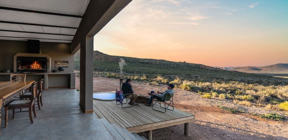 Southern Nights: Sweeping Karoo sunset deck, fire glowing, guests relaxing, sunken tub