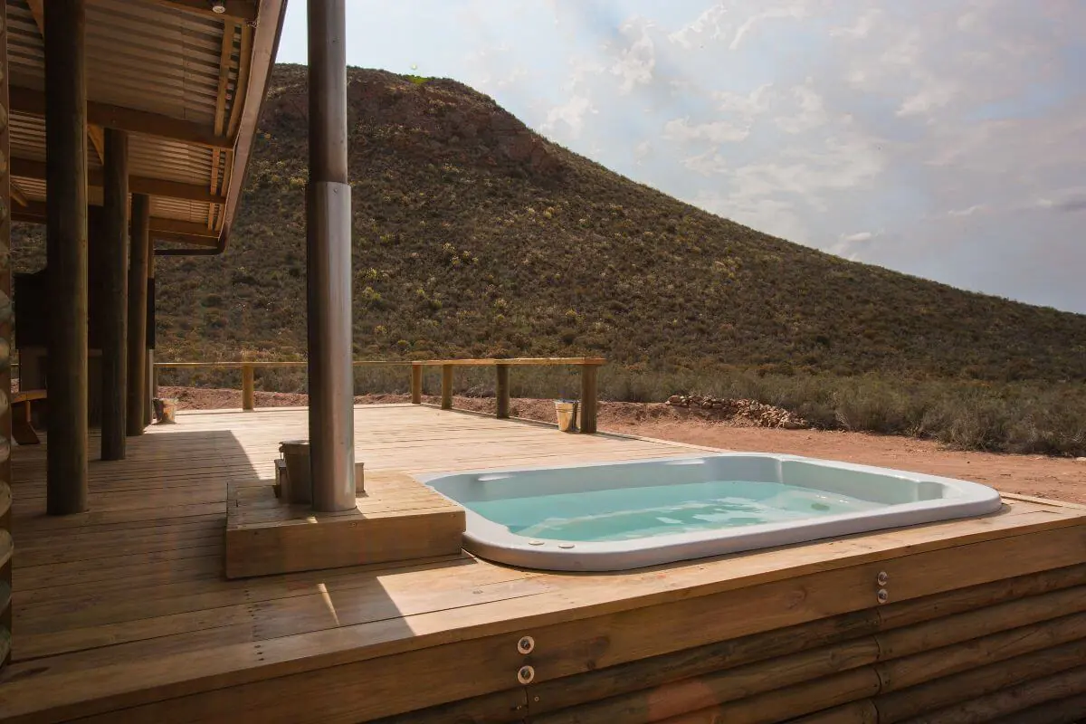 Montana Vista at Gecko Rock: Hot tub on wooden deck, Karoo hillside behind, cabin overhang left