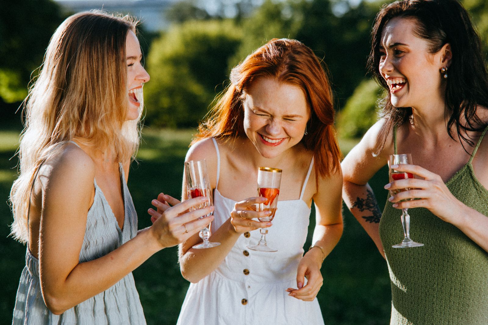 A group of friends laughing together with drinks outdoors on a getaway